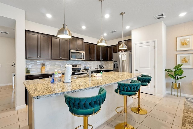 927 Paradise Dr, Davenport, FL 33897 - kitchen featuring stainless steel appliances, dark brown cabinetry, backsplash, a breakfast bar area, and recessed lighting