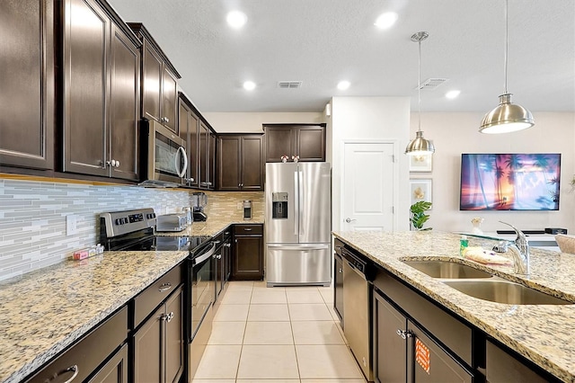 927 Paradise Dr, Davenport, FL 33897 - kitchen featuring appliances with stainless steel finishes, dark brown cabinetry, light tile patterned floors, light stone countertops, and backsplash