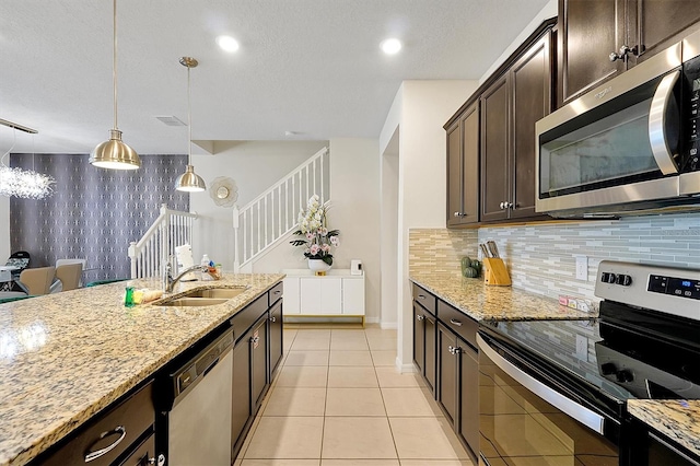 927 Paradise Dr, Davenport, FL 33897 - kitchen featuring stainless steel appliances, dark brown cabinets, light stone countertops, pendant lighting, and recessed lighting