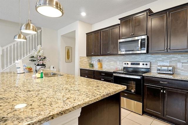 927 Paradise Dr, Davenport, FL 33897 - kitchen featuring appliances with stainless steel finishes, decorative backsplash, light stone counters, light tile patterned floors, and dark brown cabinetry