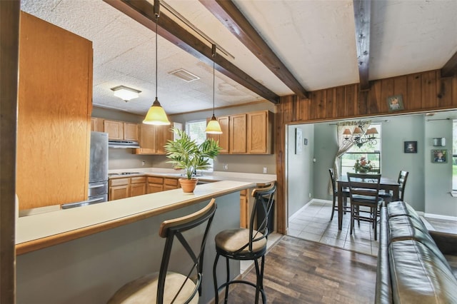 1108 W Minnehaha Ave, Clermont, FL 34711 - kitchen featuring appliances with stainless steel finishes, beam ceiling, light countertops, under cabinet range hood, and decorative light fixtures