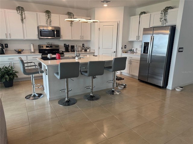 80 Citrine Loop, Kissimmee, FL 34758 - kitchen featuring appliances with stainless steel finishes, white cabinetry, light countertops, an island with sink, and a breakfast bar