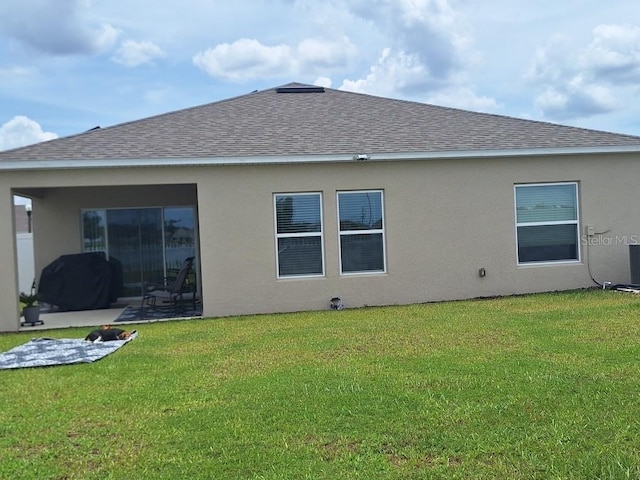 80 Citrine Loop, Kissimmee, FL 34758 - rear view of property with roof with shingles, stucco siding, a patio, and a lawn