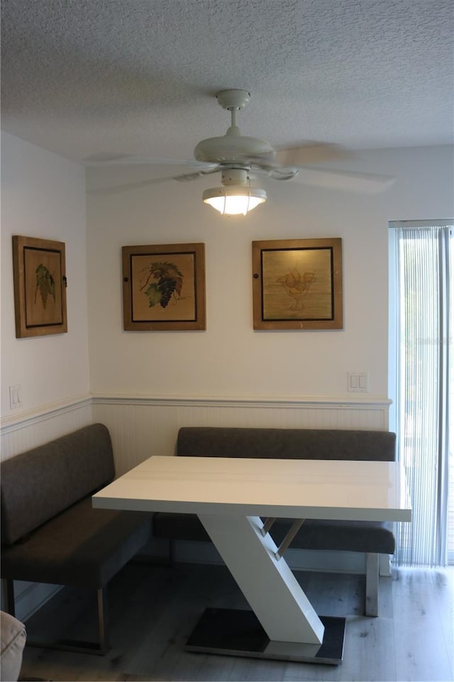 686 S Atlantic Ave Unit 1-8, Cocoa Beach, FL 32931 - dining space featuring breakfast area, a textured ceiling, wood finished floors, a wainscoted wall, and a ceiling fan