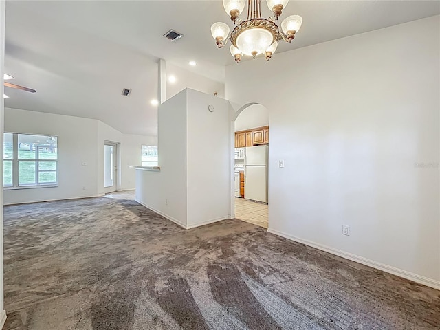 16634 Pine Timber Ave, Montverde, FL 34756 - empty room featuring light colored carpet, vaulted ceiling, a chandelier, arched walkways, and healthy amount of natural light