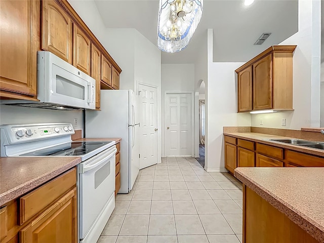 16634 Pine Timber Ave, Montverde, FL 34756 - kitchen featuring white appliances, arched walkways, light tile patterned floors, a chandelier, and brown cabinetry