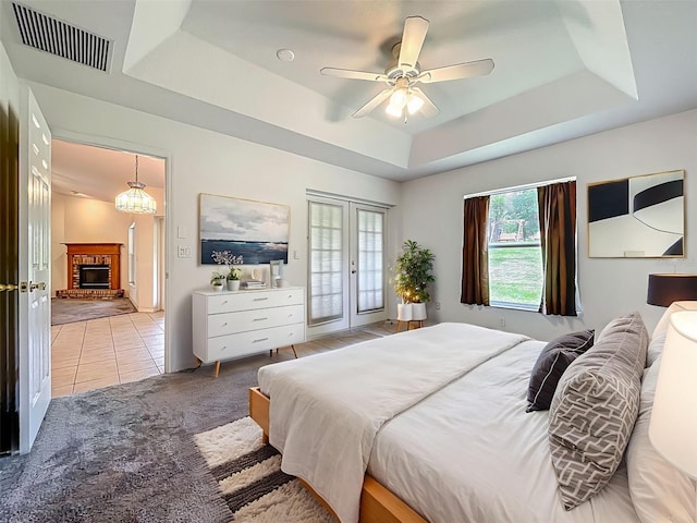 16634 Pine Timber Ave, Montverde, FL 34756 - bedroom with a tray ceiling, a brick fireplace, access to exterior, light tile patterned floors, and ceiling fan