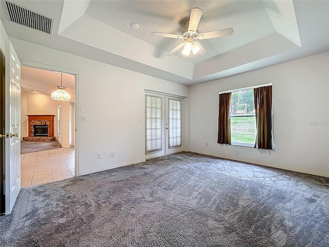 16634 Pine Timber Ave, Montverde, FL 34756 - unfurnished room featuring a tray ceiling, light colored carpet, a brick fireplace, a ceiling fan, and light tile patterned floors