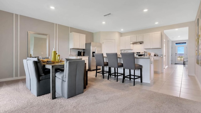 958 Princess Sabal Pt, Haines City, FL 33844 - kitchen with stainless steel fridge, under cabinet range hood, a breakfast bar, light carpet, and white cabinets