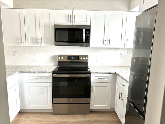 6054 Amberly Ct Unit T21, Orlando, FL 32822 - kitchen with stainless steel appliances, light wood-style floors, white cabinets, and light stone counters
