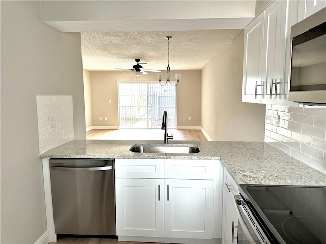 6054 Amberly Ct Unit T21, Orlando, FL 32822 - kitchen with stainless steel appliances, backsplash, light stone counters, a ceiling fan, and white cabinetry