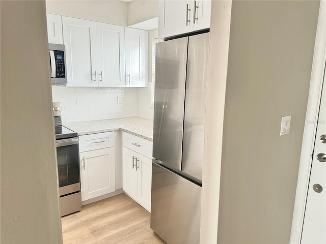 6054 Amberly Ct Unit T21, Orlando, FL 32822 - kitchen with stainless steel appliances, decorative backsplash, white cabinets, light stone countertops, and light wood finished floors