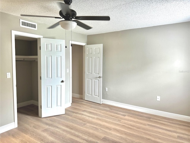 6054 Amberly Ct Unit T21, Orlando, FL 32822 - unfurnished bedroom with wood finished floors, a walk in closet, a textured ceiling, a closet, and a ceiling fan