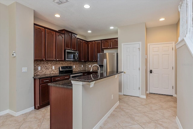 5072 Cypress Branch Pt, Oviedo, FL 32765 - kitchen with appliances with stainless steel finishes, dark stone countertops, backsplash, light tile patterned floors, and a center island with sink