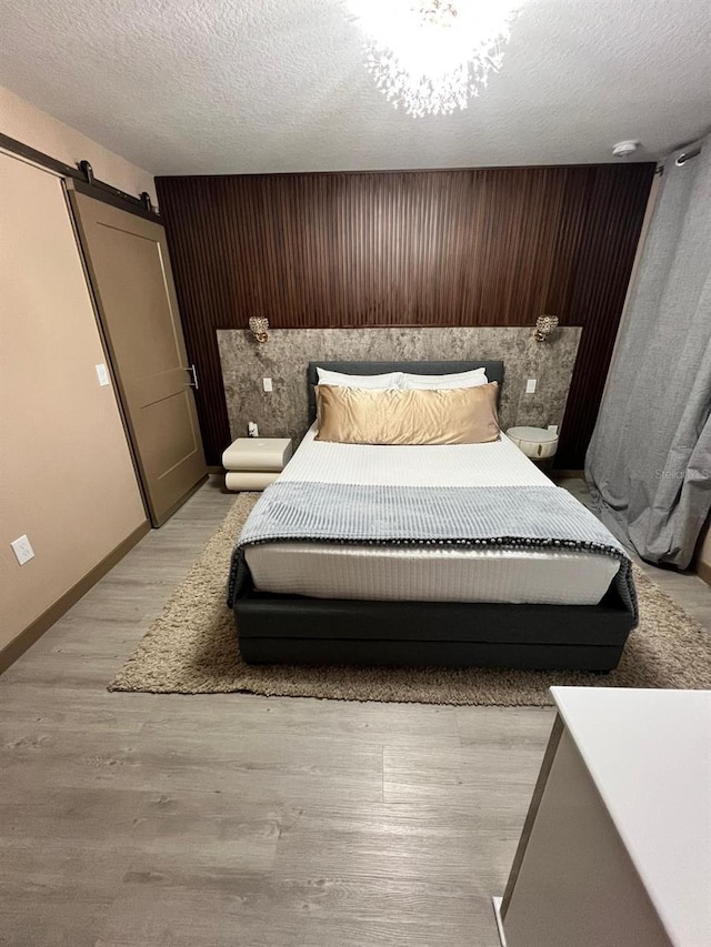 3292 Tranquil Trl, Kissimmee, FL 34747 - bedroom with a barn door, wood walls, a textured ceiling, and light wood-style floors