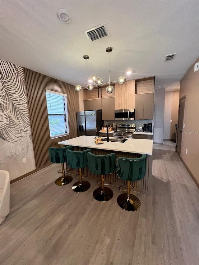 3292 Tranquil Trl, Kissimmee, FL 34747 - kitchen featuring appliances with stainless steel finishes, light wood-style floors, light countertops, and a breakfast bar area