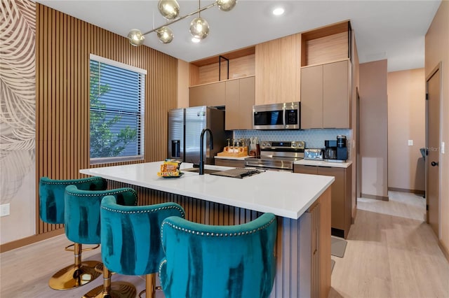 3292 Tranquil Trl, Kissimmee, FL 34747 - kitchen with appliances with stainless steel finishes, light wood-style flooring, a breakfast bar, and an island with sink
