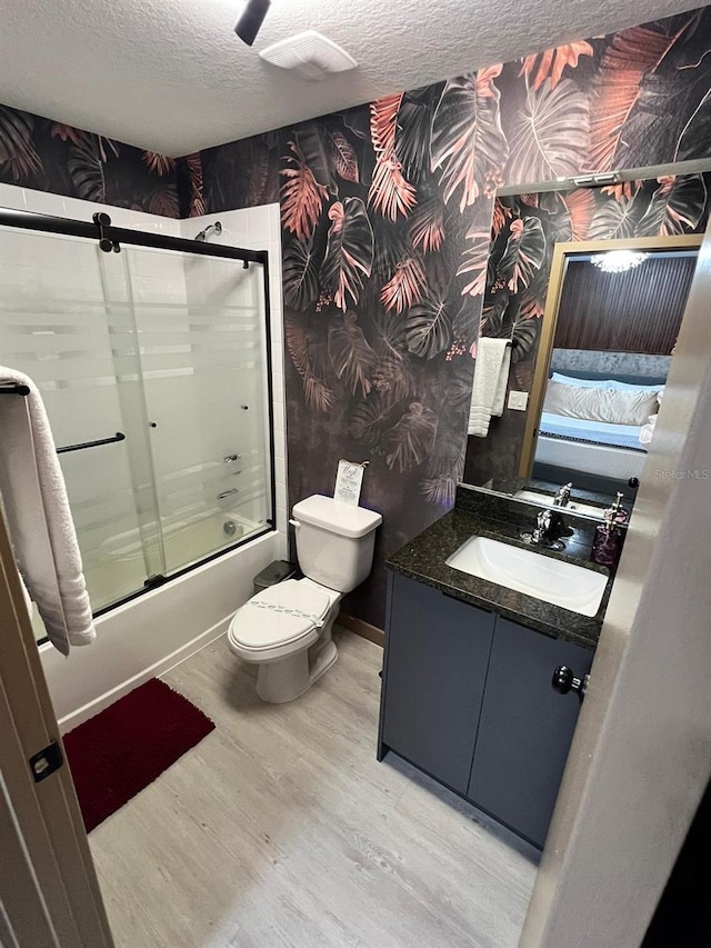 3292 Tranquil Trl, Kissimmee, FL 34747 - ensuite bathroom with wallpapered walls, a textured ceiling, bath / shower combo with glass door, wood finished floors, and vanity