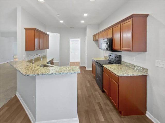 6303 Twin Bridges Dr, Zephyrhills, FL 33541 - kitchen with black electric range oven, stainless steel microwave, a peninsula, wood finished floors, and light stone counters