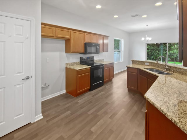 6303 Twin Bridges Dr, Zephyrhills, FL 33541 - kitchen with black appliances, brown cabinets, light stone countertops, recessed lighting, and pendant lighting