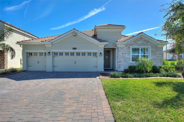 8998 Croquet Ct, Champions Gate, FL 33896 - mediterranean / spanish house with decorative driveway, a tiled roof, a garage, a front lawn, and stucco siding