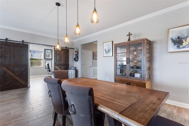 8998 Croquet Ct, Champions Gate, FL 33896 - dining room featuring a barn door, a textured ceiling, wood finished floors, and crown molding