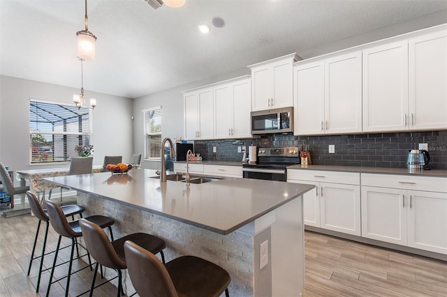 8998 Croquet Ct, Champions Gate, FL 33896 - kitchen featuring appliances with stainless steel finishes, backsplash, a chandelier, and a center island with sink