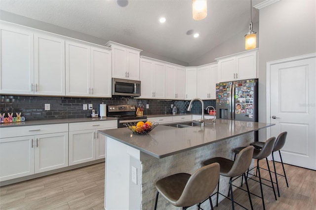 8998 Croquet Ct, Champions Gate, FL 33896 - kitchen with stainless steel appliances, light wood-style floors, decorative backsplash, a kitchen breakfast bar, and lofted ceiling