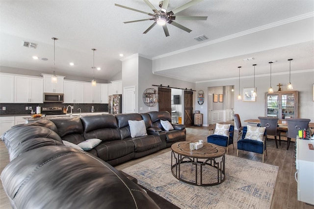 8998 Croquet Ct, Champions Gate, FL 33896 - living area with a barn door, ceiling fan, light wood-style flooring, ornamental molding, and recessed lighting