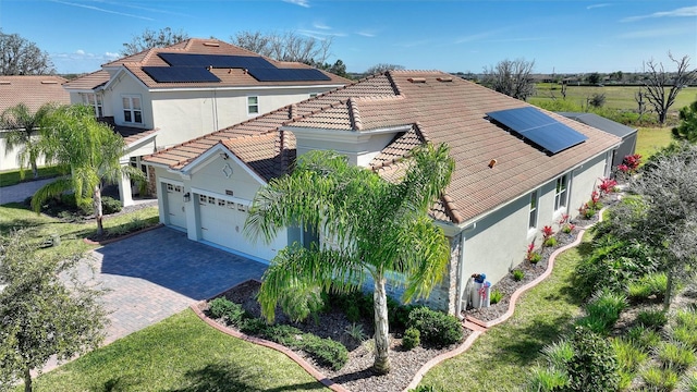 8998 Croquet Ct, Champions Gate, FL 33896 - view of side of home with stucco siding, driveway, a tile roof, roof mounted solar panels, and a garage