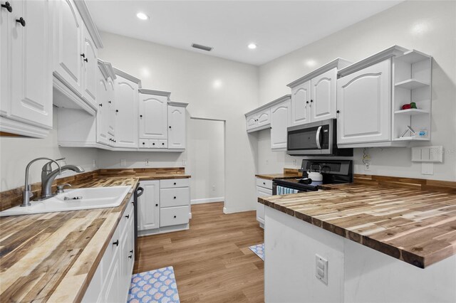12404 SW 31st Ave, Archer, FL 32618 - kitchen featuring butcher block countertops, stainless steel microwave, a peninsula, black range with electric cooktop, and light wood-style floors