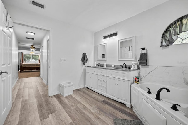 12404 SW 31st Ave, Archer, FL 32618 - ensuite bathroom featuring double vanity, a garden tub, wood finished floors, and ceiling fan
