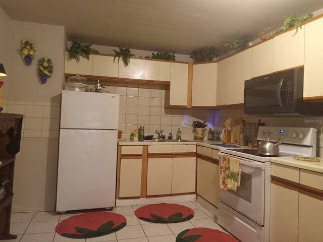 1624 Grand St, Orlando, FL 32805 - kitchen with white appliances, light countertops, light tile patterned floors, backsplash, and tile walls