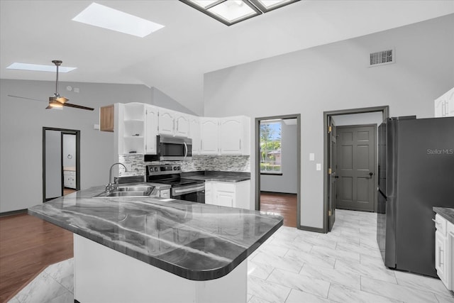 1237 Erik Ct, Altamonte Springs, FL 32714 - kitchen featuring appliances with stainless steel finishes, a skylight, a peninsula, dark countertops, and high vaulted ceiling