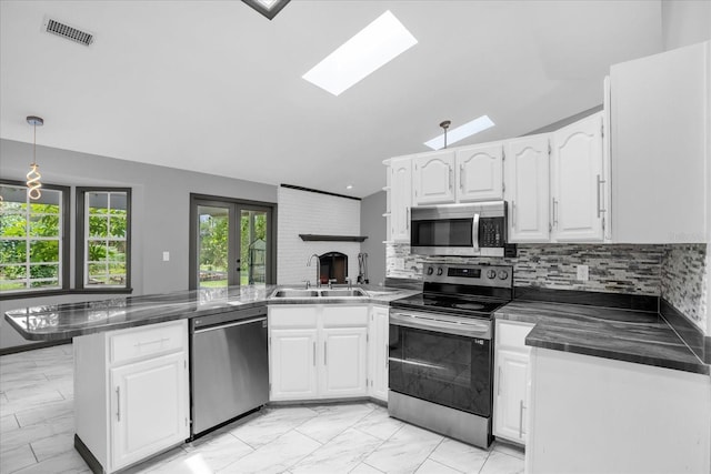 1237 Erik Ct, Altamonte Springs, FL 32714 - kitchen featuring stainless steel appliances, a peninsula, dark countertops, vaulted ceiling, and white cabinetry
