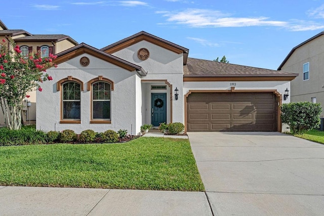 1193 Woods Landing Dr, Minneola, FL 34715 - view of front of house featuring an attached garage, a front yard, concrete driveway, and stucco siding
