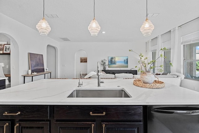 1193 Woods Landing Dr, Minneola, FL 34715 - kitchen featuring open floor plan, dark cabinets, dishwasher, arched walkways, and hanging light fixtures