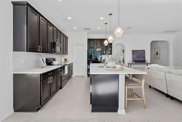 1193 Woods Landing Dr, Minneola, FL 34715 - kitchen with black appliances, arched walkways, open floor plan, decorative backsplash, and recessed lighting