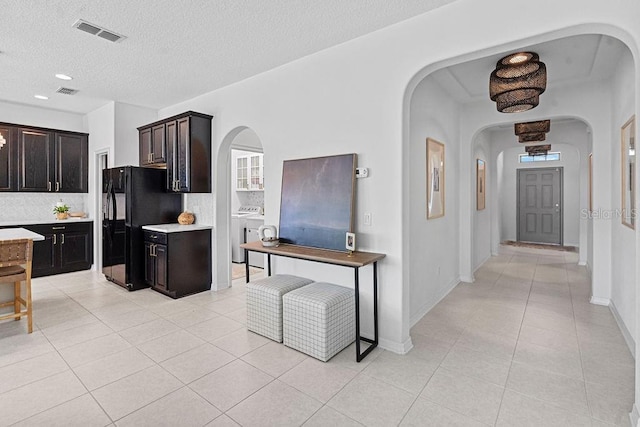 1193 Woods Landing Dr, Minneola, FL 34715 - kitchen featuring arched walkways, freestanding refrigerator, light tile patterned flooring, decorative backsplash, and a textured ceiling