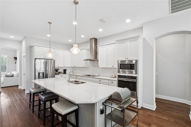 16415 Good Hearth Blvd, Clermont, FL 34711 - kitchen with appliances with stainless steel finishes, arched walkways, wall chimney range hood, dark wood finished floors, and recessed lighting