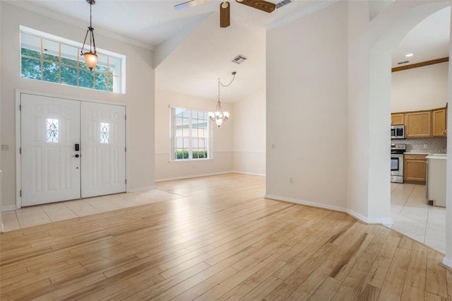 6029 Falconbridge Pl, Mount Dora, FL 32757 - foyer entrance featuring arched walkways, a ceiling fan, light wood-style flooring, a chandelier, and a towering ceiling