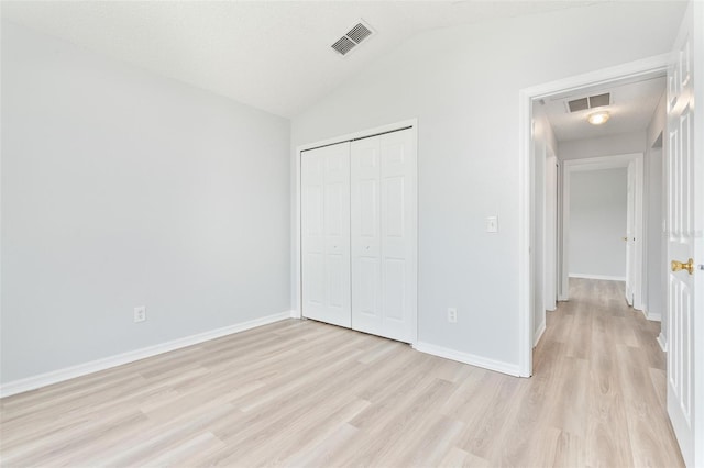 313 Cheshire Way, Davenport, FL 33897 - unfurnished bedroom with light wood-type flooring, lofted ceiling, and a closet