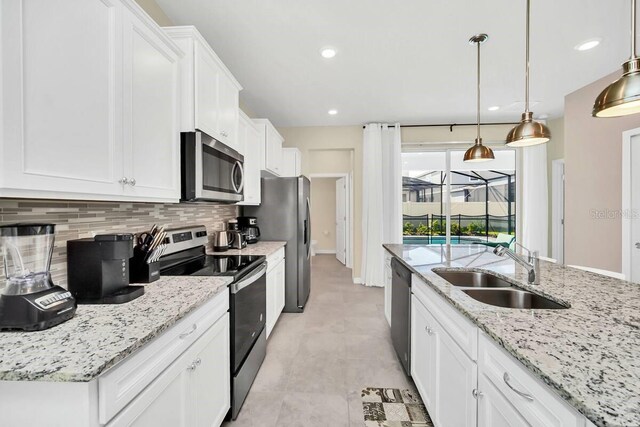 3448 Lilac Way, Davenport, FL 33897 - kitchen with appliances with stainless steel finishes, decorative backsplash, white cabinetry, light stone countertops, and hanging light fixtures