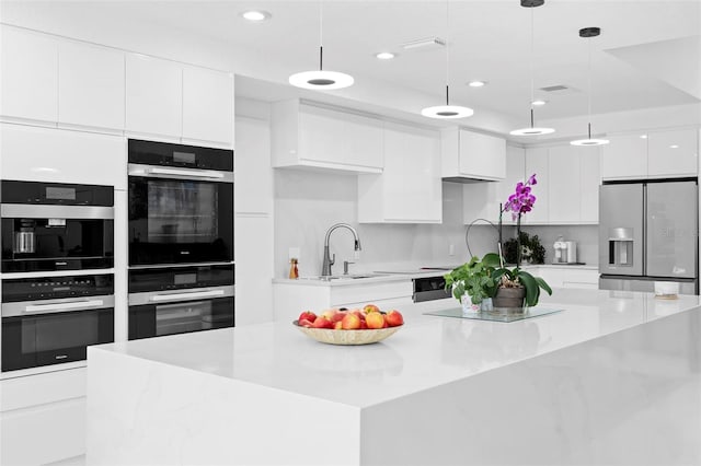 7905 Chad Ct, Orlando, FL 32835 - kitchen with stainless steel appliances, modern cabinets, white cabinetry, recessed lighting, and a large island with sink