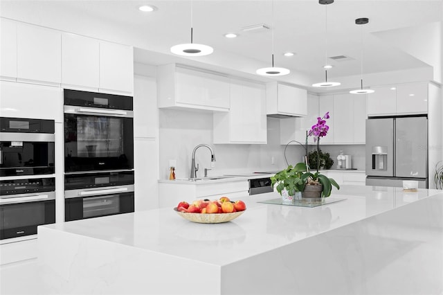7905 Chad Ct, Orlando, FL 32835 - kitchen with appliances with stainless steel finishes, modern cabinets, white cabinets, hanging light fixtures, and recessed lighting