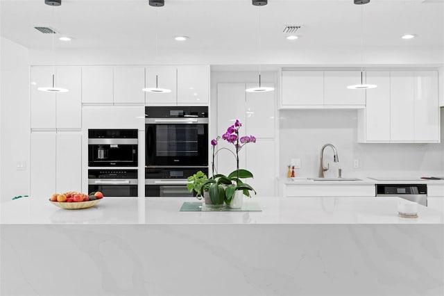 7905 Chad Ct, Orlando, FL 32835 - kitchen featuring modern cabinets, white cabinetry, appliances with stainless steel finishes, hanging light fixtures, and recessed lighting