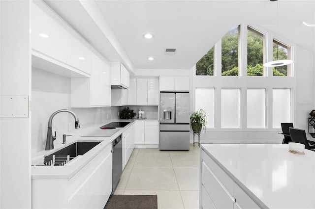 7905 Chad Ct, Orlando, FL 32835 - kitchen with stainless steel appliances, white cabinets, light tile patterned floors, light countertops, and decorative backsplash