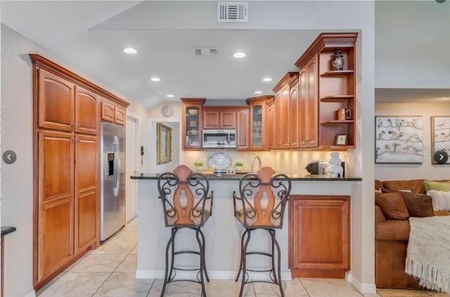 7905 Chad Ct, Orlando, FL 32835 - kitchen featuring appliances with stainless steel finishes, a peninsula, dark countertops, glass insert cabinets, and a breakfast bar