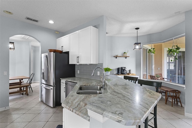 11337 Via Andiamo, Windermere, FL 34786 - kitchen featuring appliances with stainless steel finishes, arched walkways, light tile patterned flooring, white cabinets, and a textured ceiling