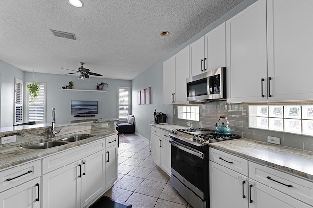 11337 Via Andiamo, Windermere, FL 34786 - kitchen with appliances with stainless steel finishes, ceiling fan, healthy amount of natural light, backsplash, and a textured ceiling